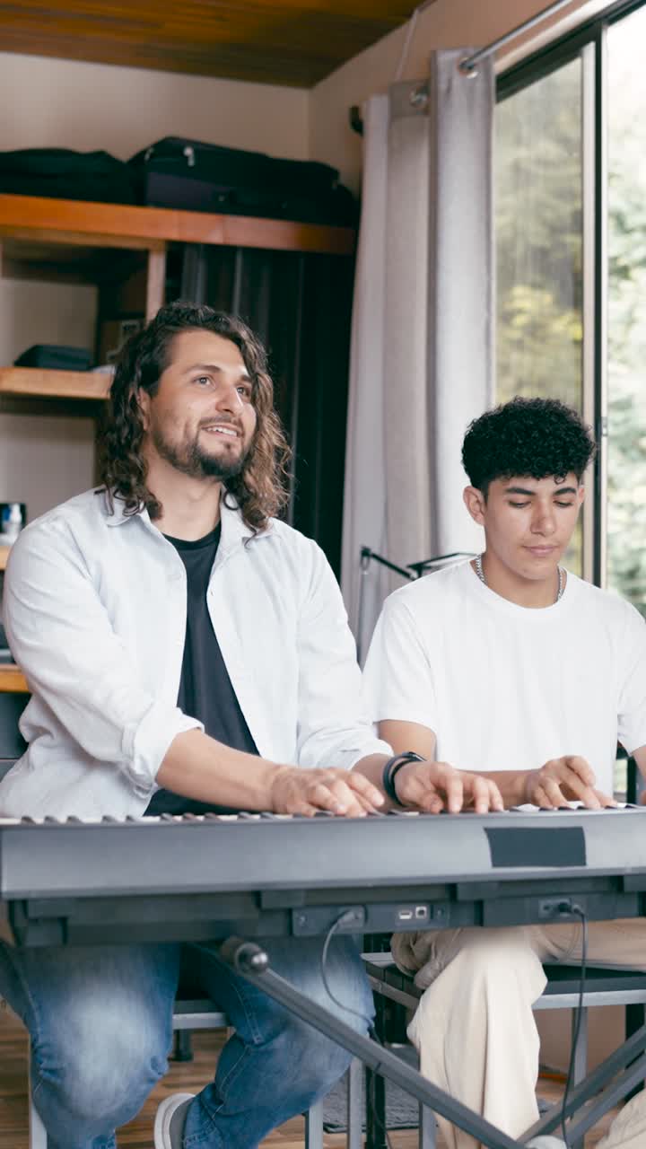 Two people playing a keyboard indoors