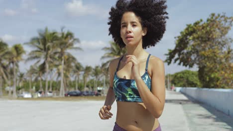 Black-fit-girl-jogging-on-tropical-waterfront