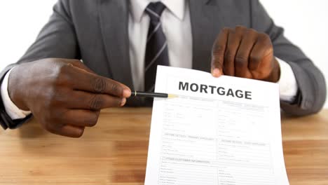 agent sitting at desk holding mortgage contract