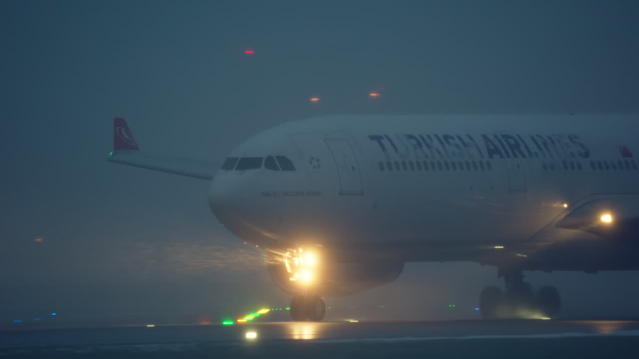 Aereo di linea della Turkish Airlines in rullaggio su una pista nebbiosa.