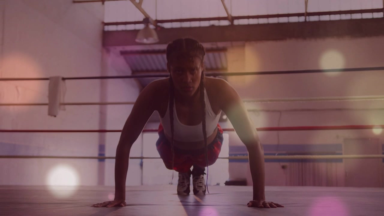 Woman starting plank and doing pushups in boxing ring with bokeh overlay showing form for training