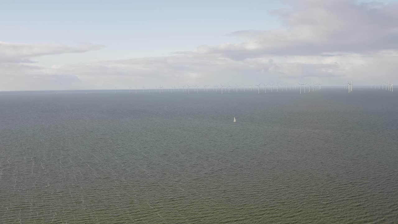 아름다운 화창한 날 네덜란드의 바다에 있는 대형 풍력 발전소 근처에 있는 범선의 공중 촬영