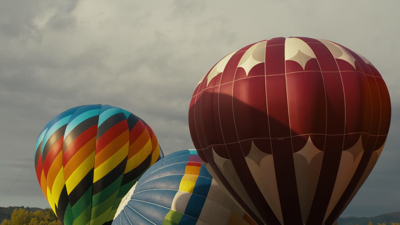 coloridos globos de aire caliente completamente inflados y esperando para despegar del suelo al amanecer o al atardecer con nubes en el fondo
