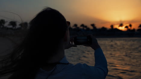 mujer joven usando teléfono móvil en la playa de verano. chica bonita tomando fotos.