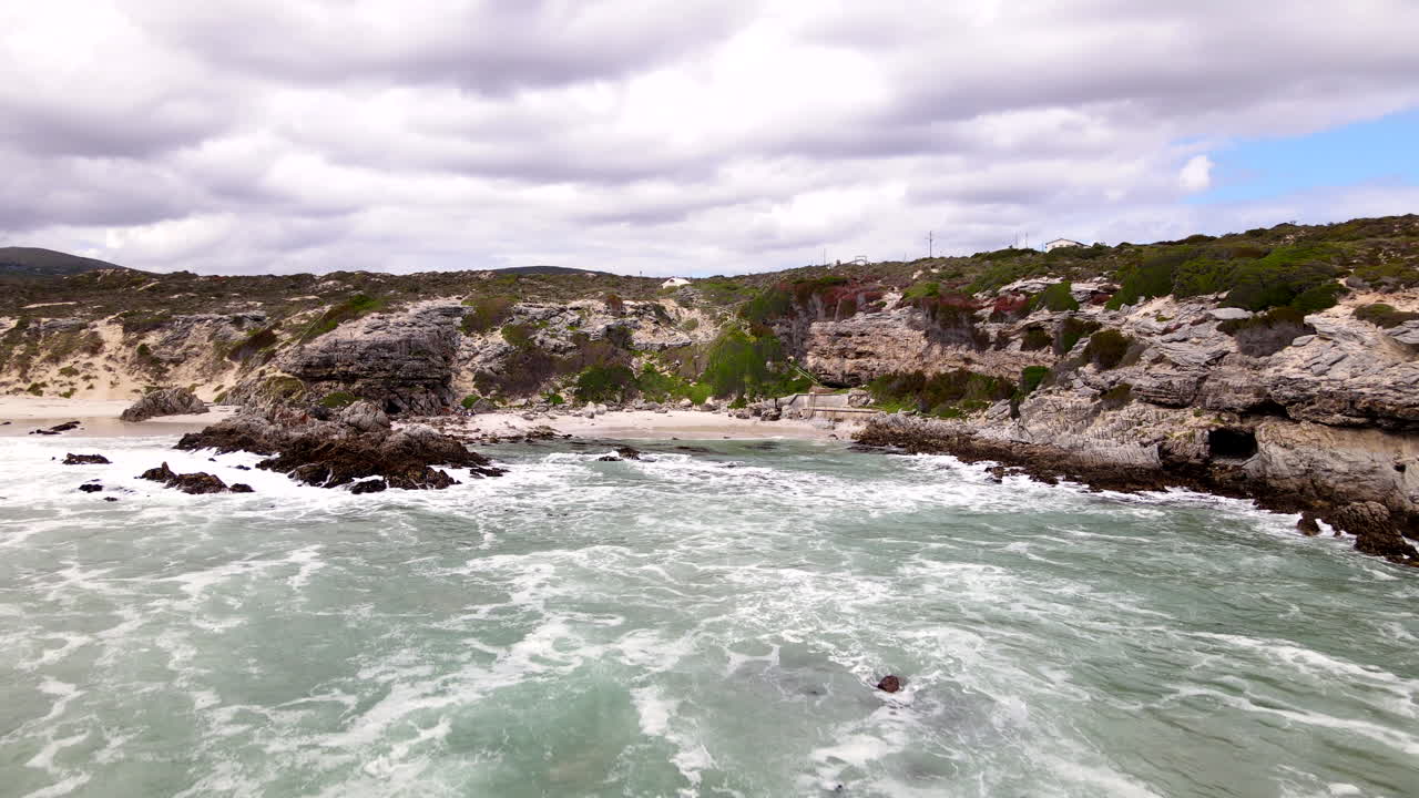 Drone dolly over ocean toward Klipgat Cave and Die Plaat coastline, De Kelders