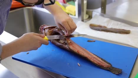 close up of the chef hands skinning and cutting the fish