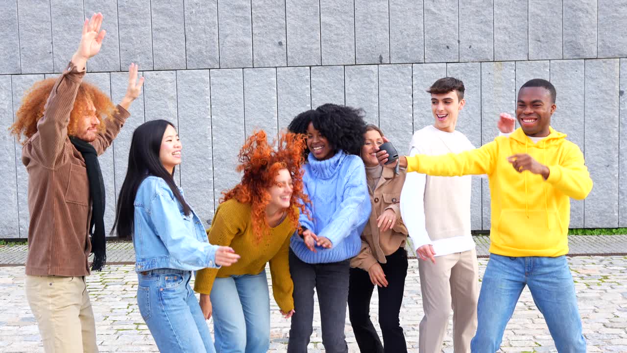 A group of diverse young adults dancing and celebrating together outdoors