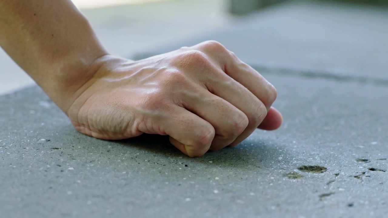 Sollevando una mano adulta che arriccia le dita sondando una piccola cavità su una lastra di cemento, con il polso che controlla la consistenza