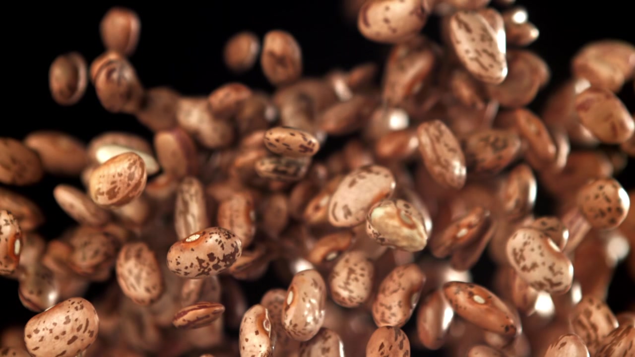 Raw Pinto Beans Falling in Slow Motion Against Black Background