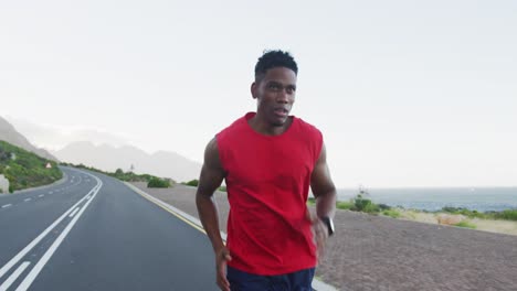 African-american-man-exercising-outdoors-running-on-a-coastal-road