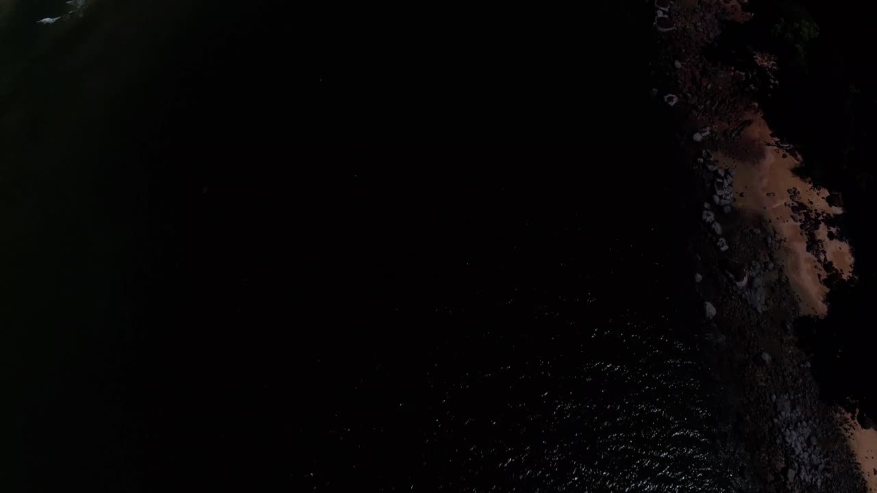 pasando por una playa rocosa con coloridas arenas de playa con movimiento panorámico para revelar montañas ondulantes y paisajes.