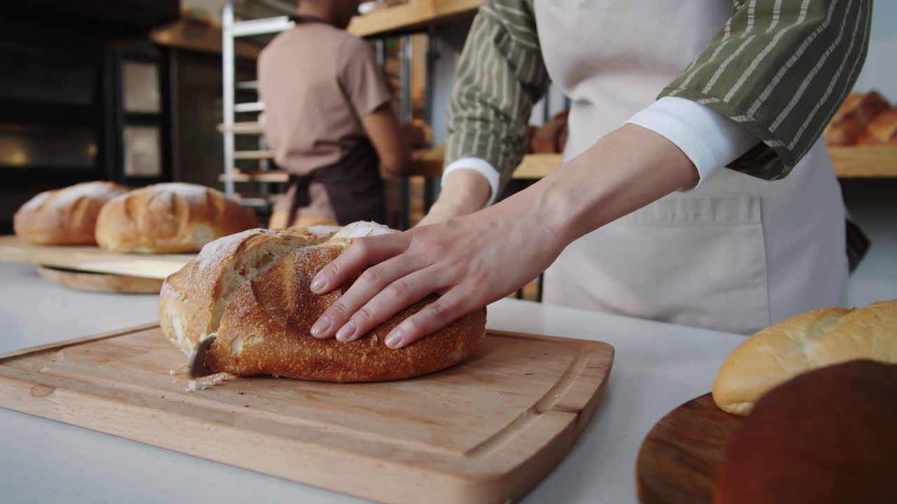Woman Cutting Loaf of Bread in Bakery