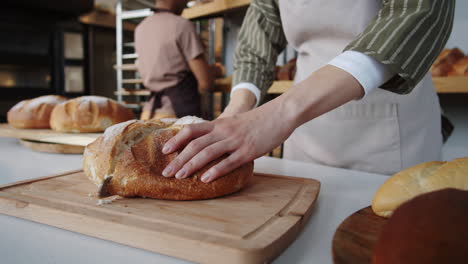 Woman-Cutting-Loaf-of-Bread-in-Bakery