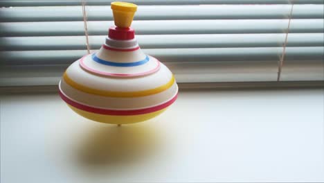 Spinning whirligig, child toy on background of blinds.