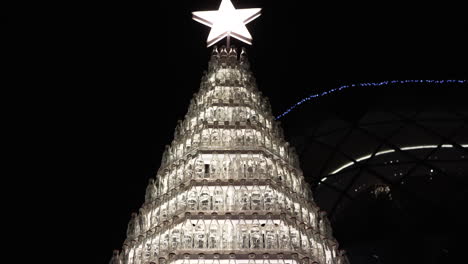 original christmas tree made of recycled glass bottles is illuminated by a bright star