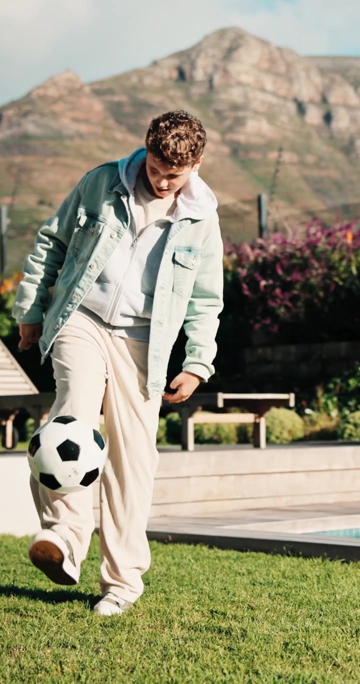 Giovane uomo che palleggia con un pallone da calcio in un giardino soleggiato