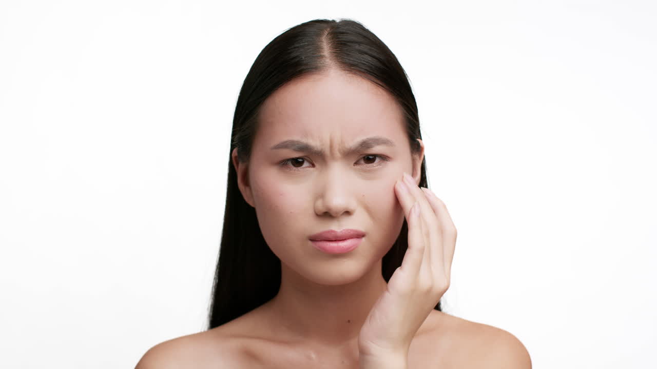 Close-up of a woman experiencing pain or discomfort, holding her temple