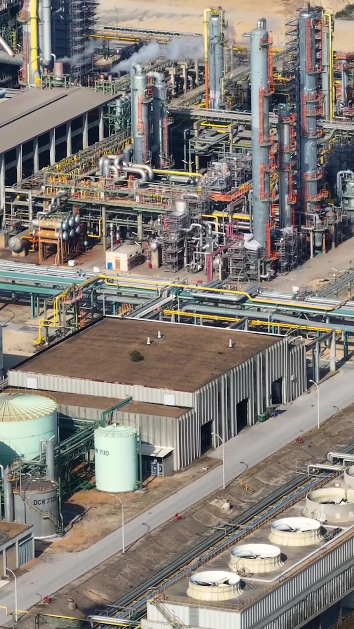 The video shows an oil refinery complex with oil tanks and processing units. The industrial facility highlights operations in the petrochemical industry during daylight.