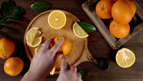 hands man with a knife cut ripe orange into two halves.