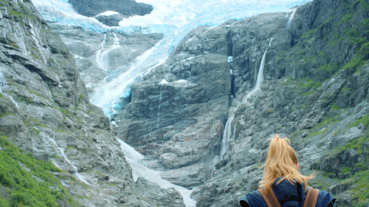mujer caminando en un fiordo noruego con fondo de glaciar