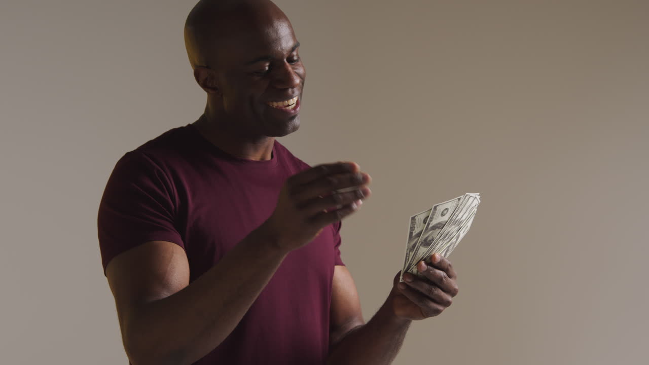 Studio Shot Of Excited Mature Man Celebrating Winning Cash Prize Kissing And Throwing Handful Of 100 Dollar Bills In The Air