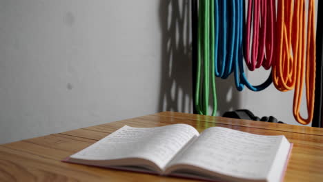 open notebook on wooden table with colorful ropes background