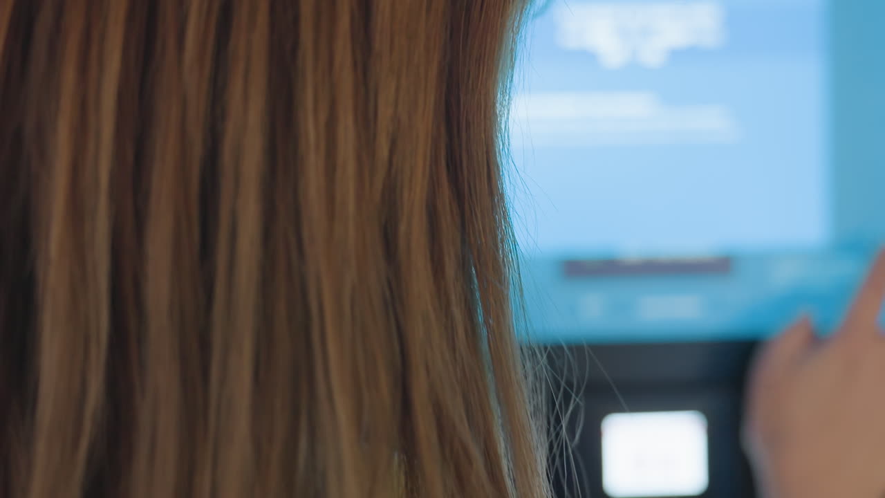 Close up rear view of service woman operating blur touch screen machine, finger presses buttons on interface, blue glow from display, indoor self service payment terminal, modern technology workflow