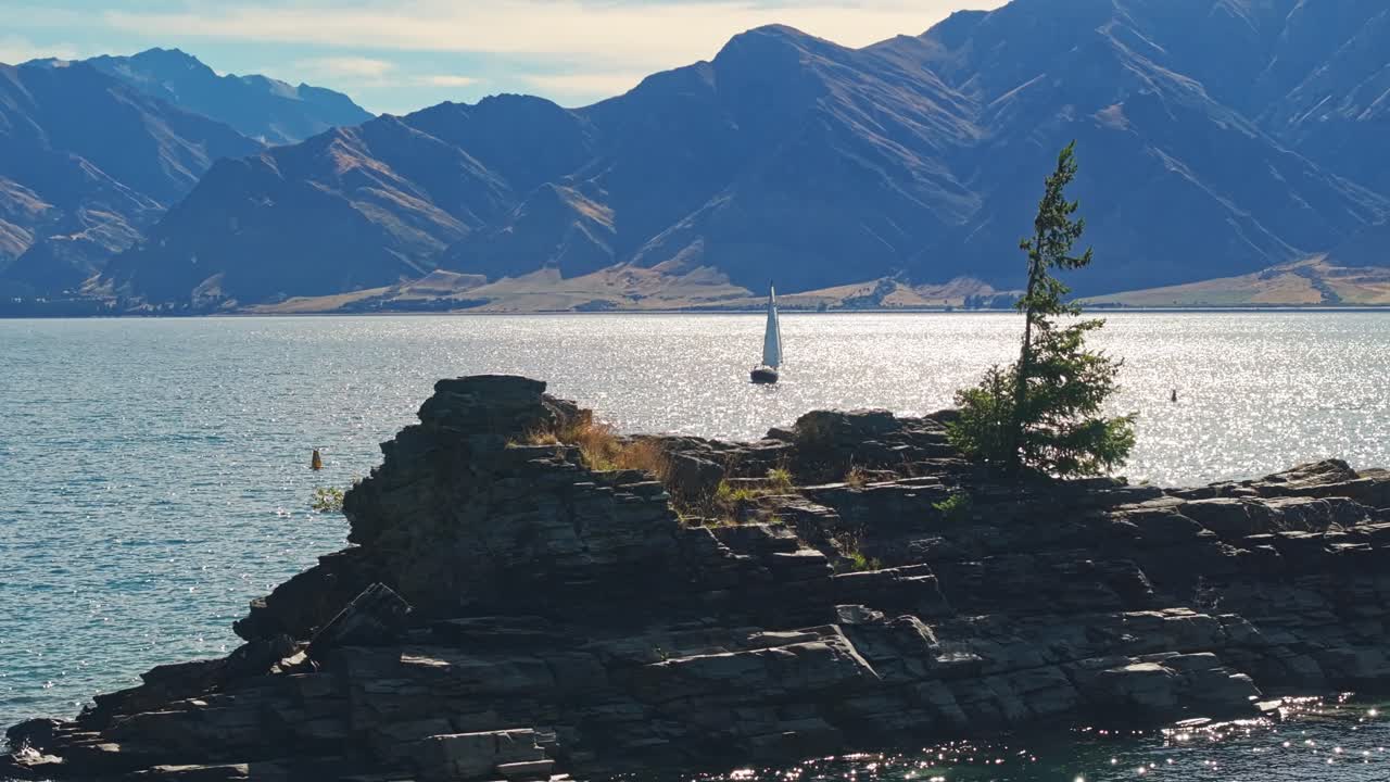 velero enmarcado entre el borde rocoso de una pequeña isla en el lago hawea nueva zelanda