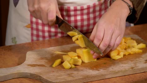 Cutting-zucchini-on-a-wooden-cutting-board-in-the-kitchen-by-a-young-woman