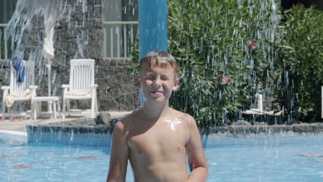 Niño-Refrescante-Bajo-La-Cascada-En-La-Piscina-Exterior