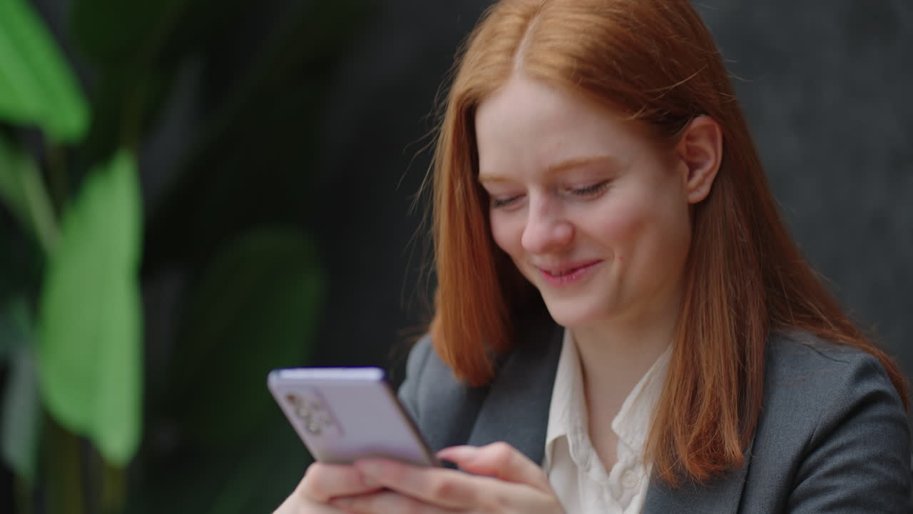 красивая рыжая женщина использует смартфон во время рабочего дня в офисе женщина просматривает социальные сети