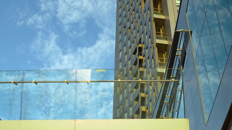 Architettura moderna di grattacieli in vetro e acciaio contro un cielo blu con nuvole.
