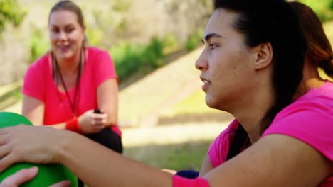 entrenadora que instruye a las mujeres mientras hacen ejercicio durante una carrera de obstáculos