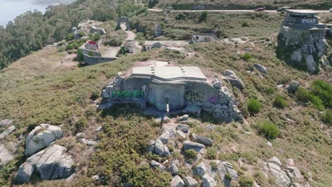 Toma-Aérea-De-Drones-En-Movimiento-Hacia-Atrás-De-Viejos-Búnkeres-Abandonados-Del-Ejército-Con-Cañones-Usados-En-La-Guerra-Civil-Española-A-Lo-Largo-Del-Terreno-Montañoso-A-Lo-Largo-De-La-Costa-Durante-El-Día