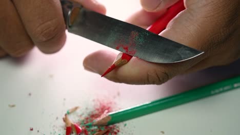 Footage-of-hands-slowly-sharpening-a-pencil-and-some-coloured-pencils-with-a-sharp-knife