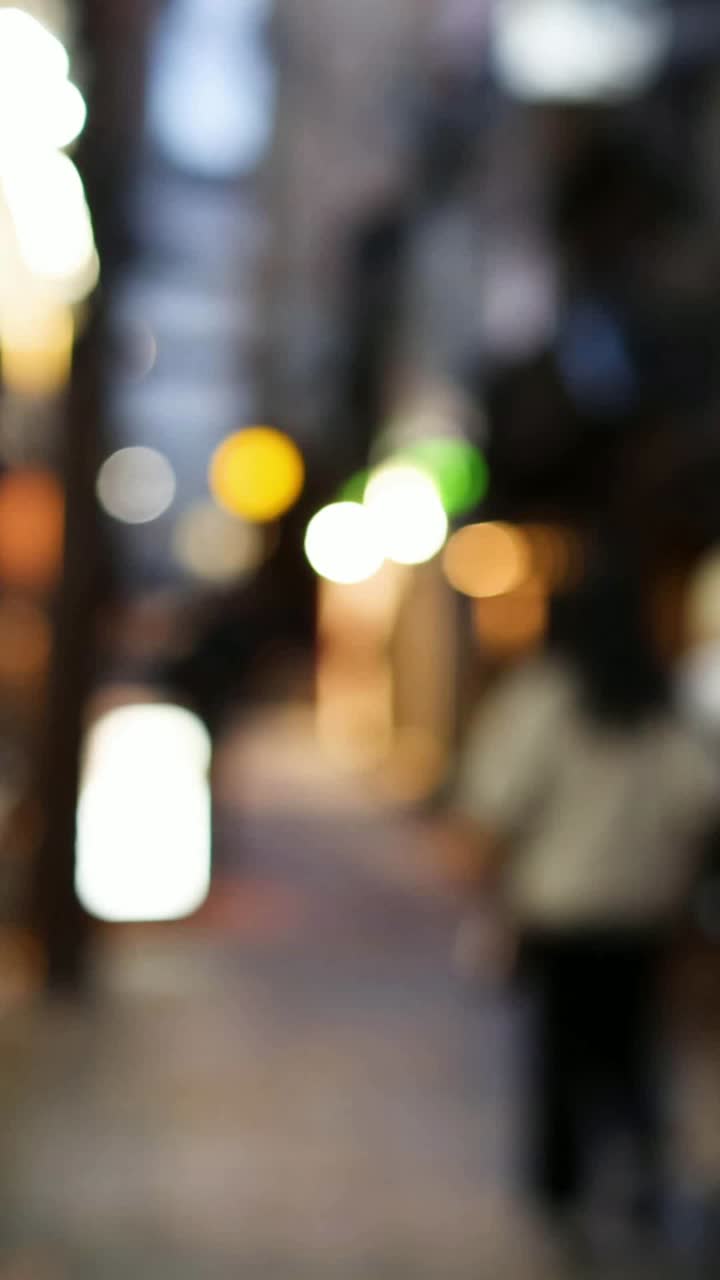 figuras fuera de foco caminando por un callejón iluminado
