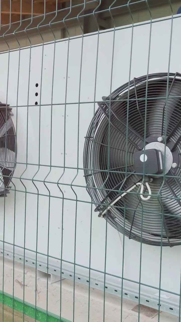 Industrial Cooling Fans Mounted on Exterior Wall Behind Security Fence