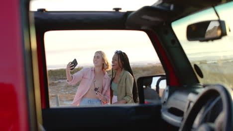 una joven afroamericana y una mujer caucásica se toman una selfie en un coche.