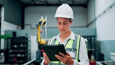 female engineer inspecting robotic arm in factory