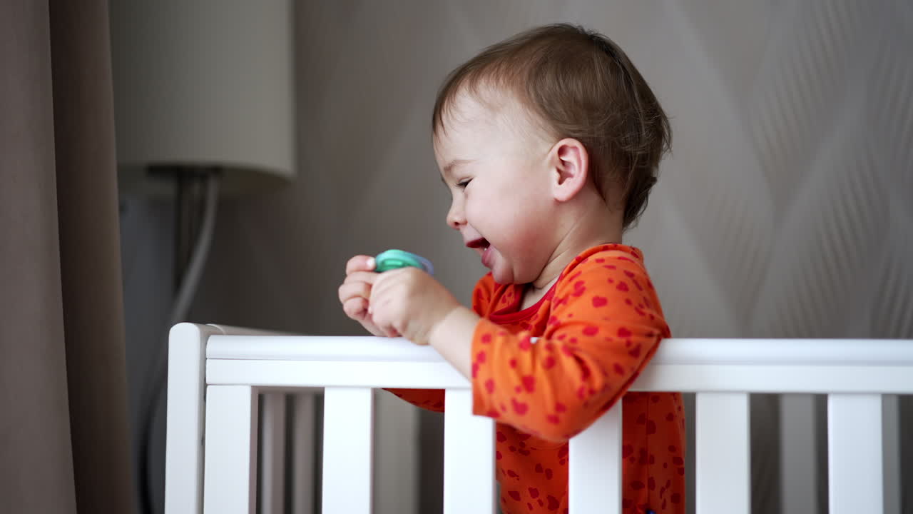 Baby in a crib playing with pacifier