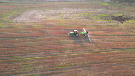 Toma-Aérea-De-Un-Tractor-Rociador-Verde-Que-Rocía-Tierras-Agrícolas