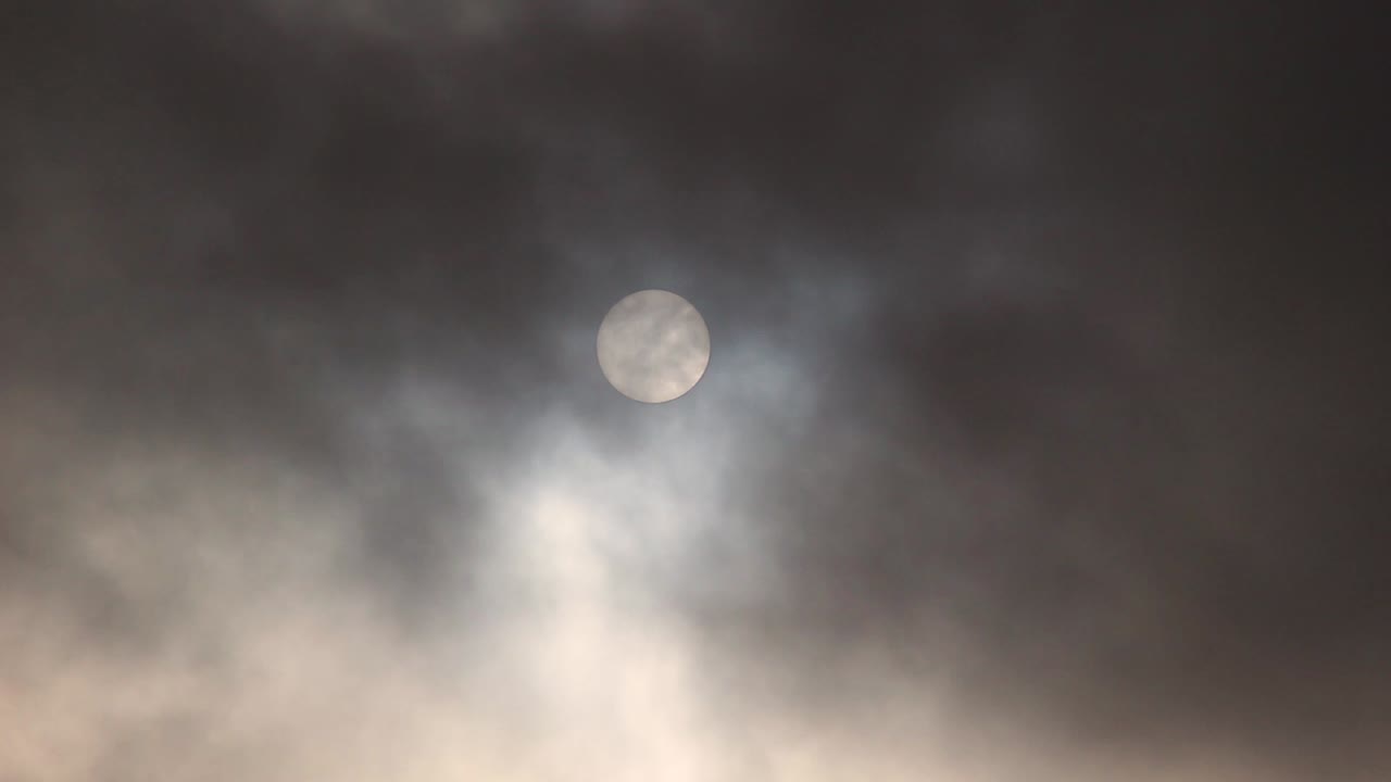 Sun behind dark clouds zoomed footage