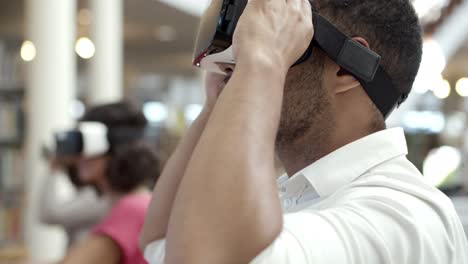 hombre afroamericano sonriente experimentando nuevas gafas vr