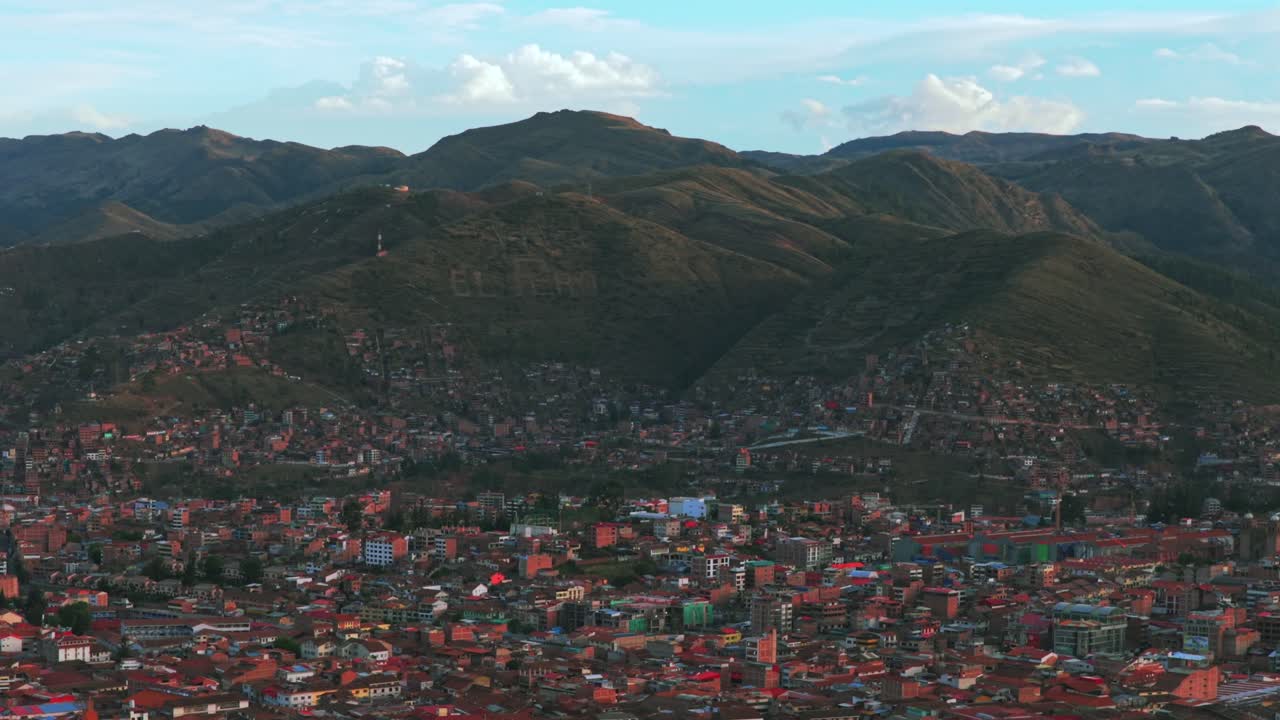 Cusco city Plaza De Armas street cityscape buildings Peru aerial drone late vive en el cusco mountain hillside Cuzco Saqsaywaman Anta province afternoon sunset rainy season clouds blue sky backwards