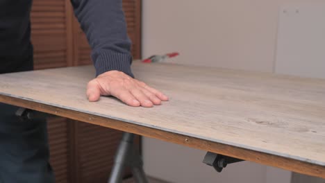 man planes vinyl floors to the desired size while doing odd jobs in his home