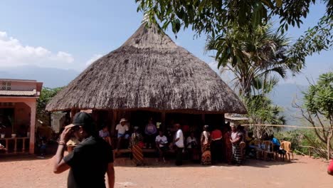 a remote timorese family and village community sitting at traditional thatched roof sacred house in timor leste, southeast asia