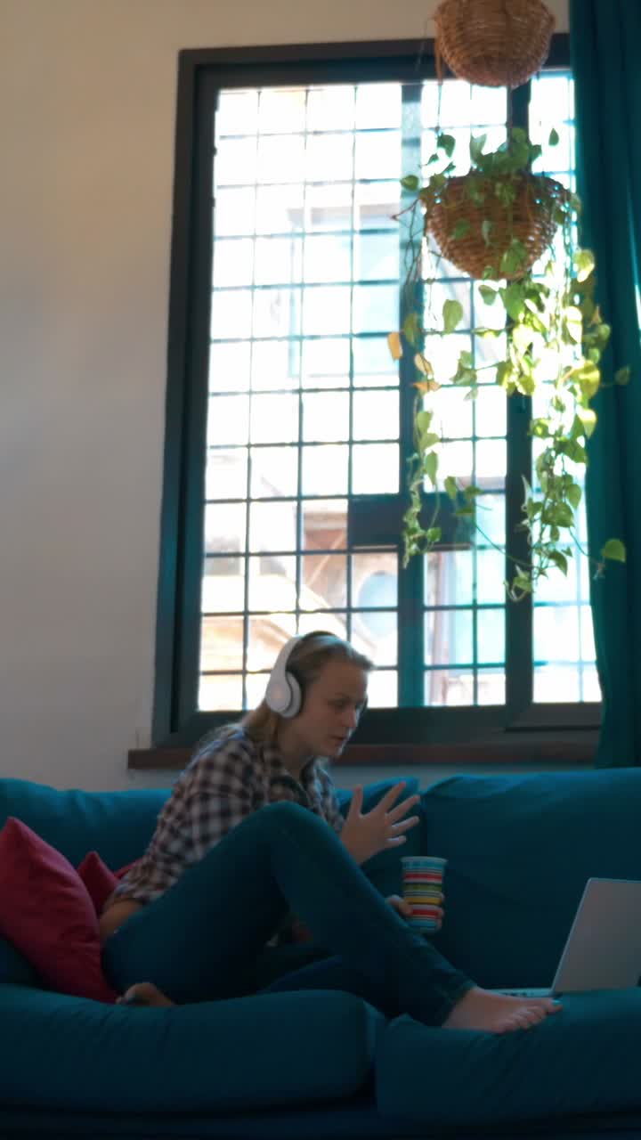 Kanepede kulaklıkla laptop kullanan kadın