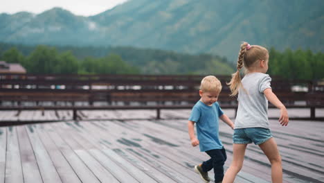 Una-Niña-Con-Un-Hermano-Menor-Corre-Por-Una-Plataforma-De-Madera