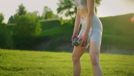 a close-up of a young woman crouching with dumbbells in a park at sunset. one woman trains in the park. the concept of sports healthy eating and lifestyle