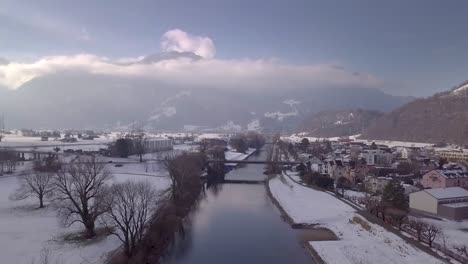 Aufsteigender-Schuss-über-Einen-Geraden-Kanal-Und-Ein-Sehr-Kleines-Dorf-In-Der-Schweiz